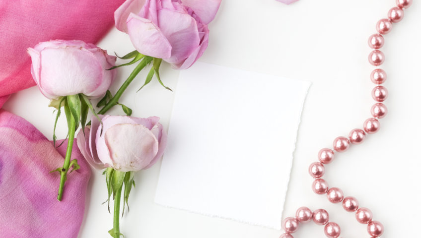 pink roses and pearl necklace on white background
